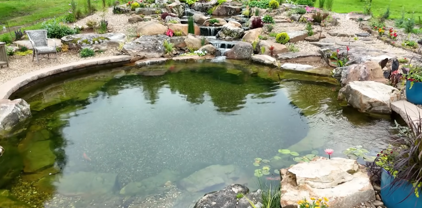 Lago com cascata, pedras e vegetação no entorno